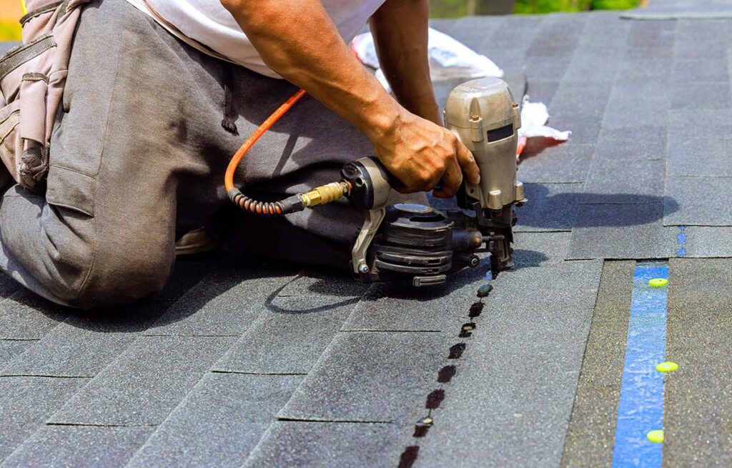 roofer adding shingles to a roof