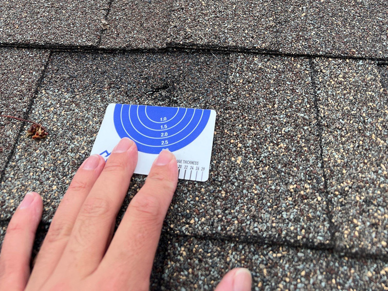 Hand measuring hail damage on beavercreek ohio home